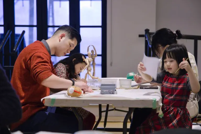 A photograph of a father, two daughters and mother at a table working on art projects in The Making Place