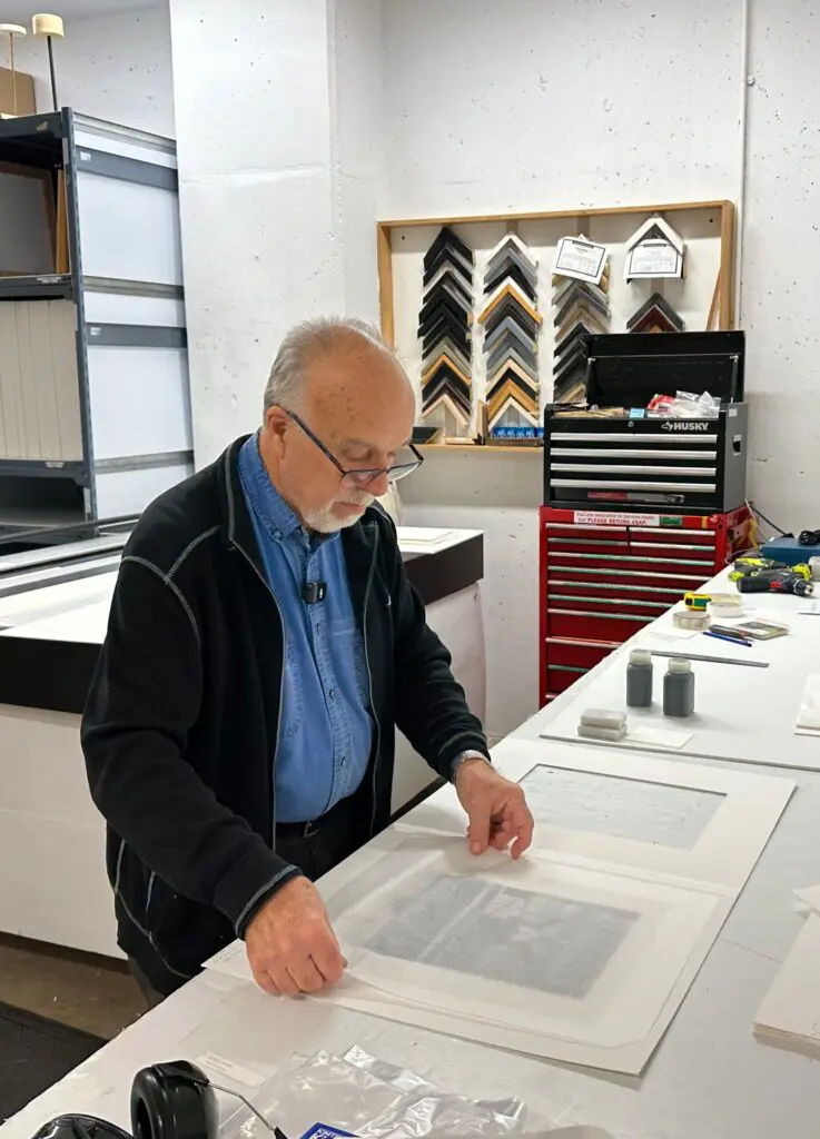 Michael Trevillion, Preparation Department staff, at work matting a painting.