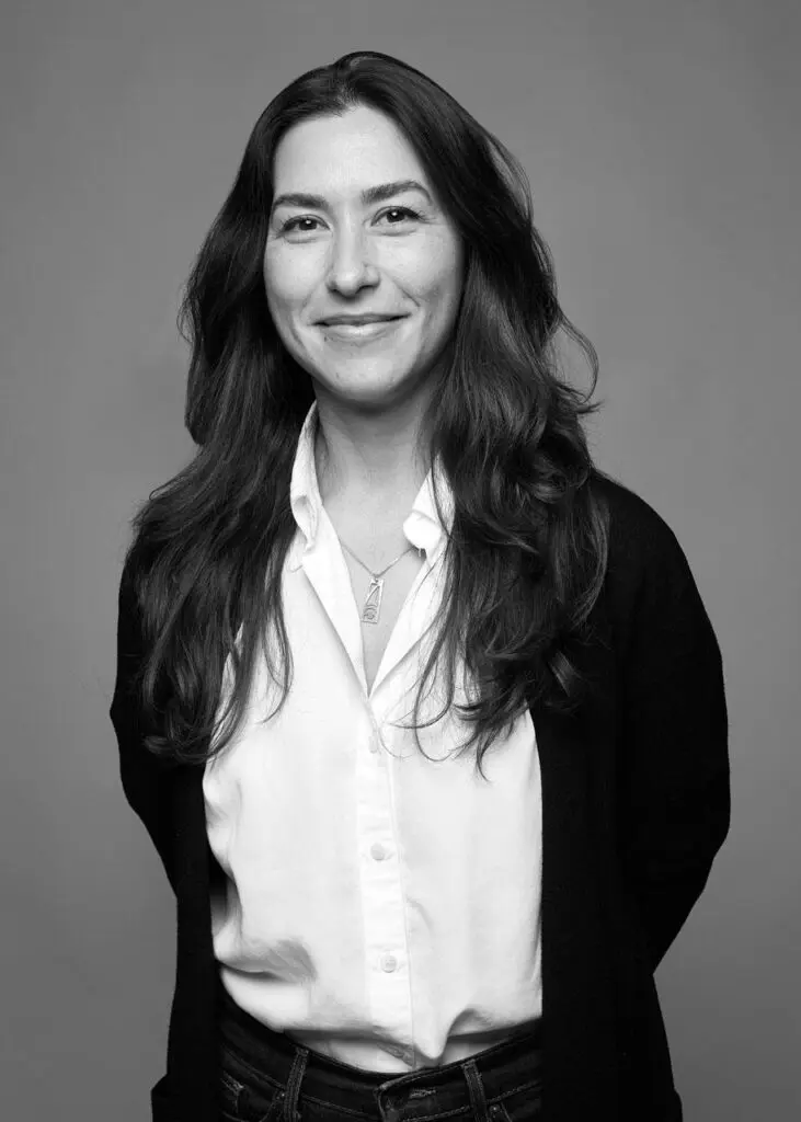 Black-and-white headshot of Dr. Camille Georgeson-Usher, a woman of Indigenous heritage with long brown hair, wearing a white button-up blouse and a black cardigan.