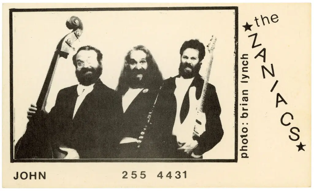 Business card for the band the Zaniacs featuring a black-and-white image of 3 men with instruments.
