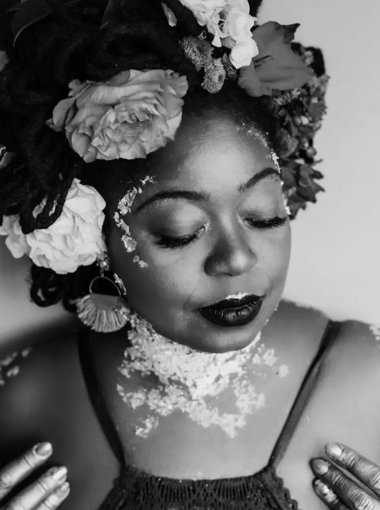 Black-and-white portrait of Jillian Christmas, wearing a flower crown and painted with gold.