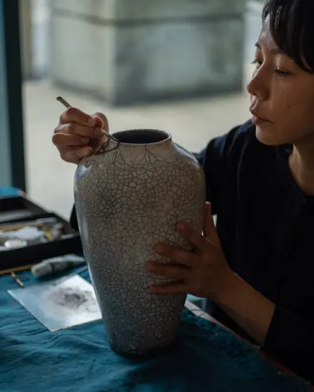 Photo of artist Yuka Morino using the kintsugi technique on a ceramic vase.