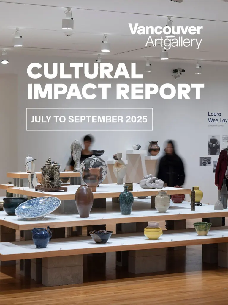 An installation view of Written In Clay. People walk around the room and discover platforms of shelves with many colourful vases and ceramics on them.