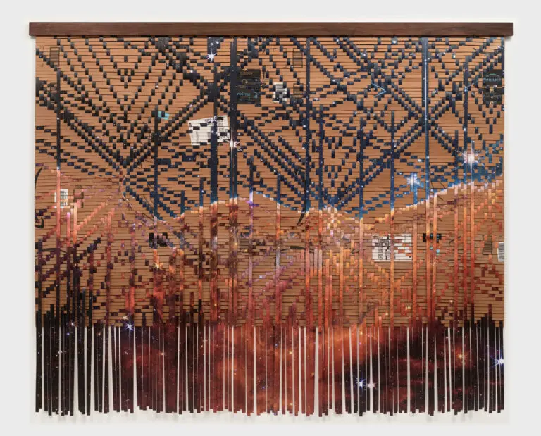 A photograph of an artwork that appears to be a hanging tapestry or weaving, but it is made up of used Amazon.com delivery boxes and paper.