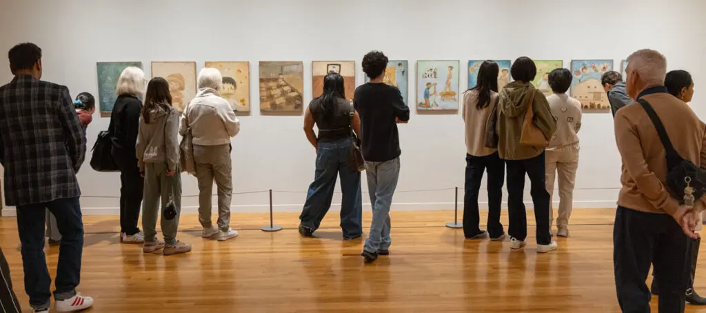 A photograph of many people of all ages visiting the Gallery, standing and looking at art on the wall