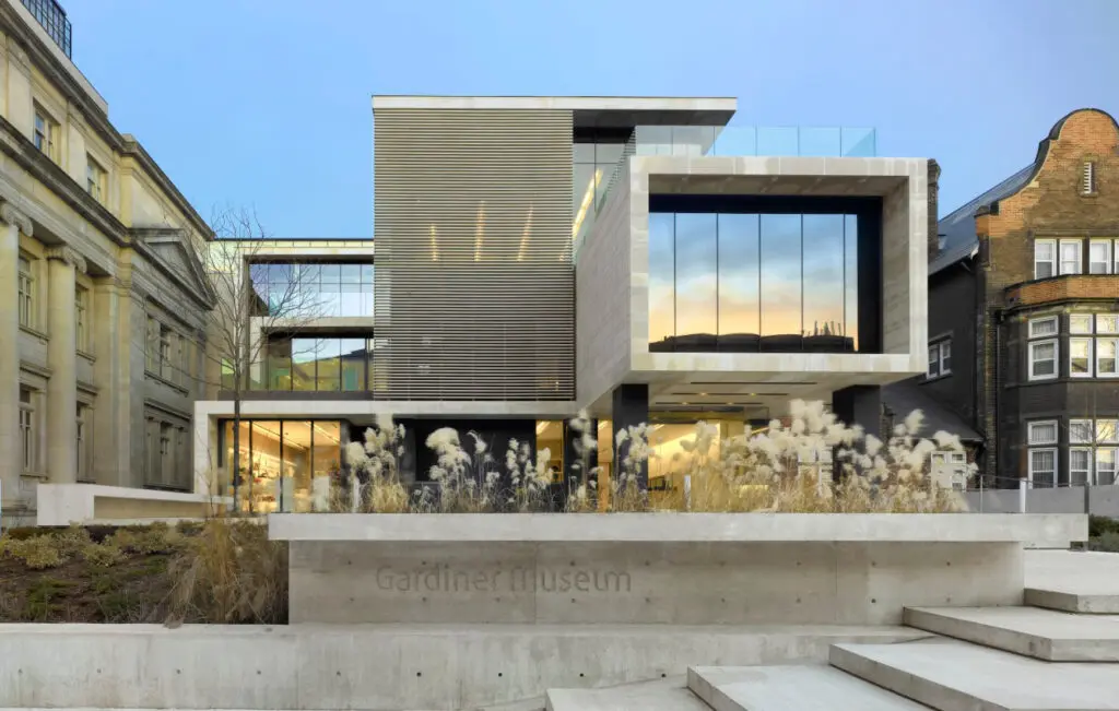 A photograph of the Gardiner Museum from the front, a concrete building that is made up of 3 rectangular forms. The building has large front-facing windows.