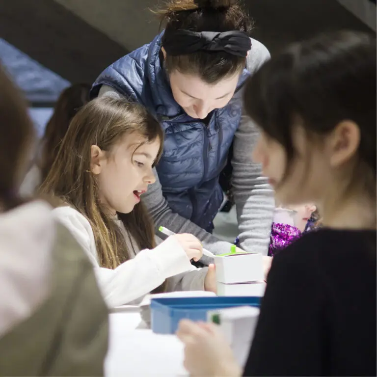 Square image of a child and her mother doing a making activity at the gallery