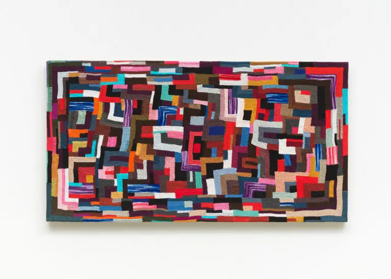 A photograph of a textile artwork by Canadian artist Jan Wade. The piece is a colourful, hand-sewn work, stretched on canvas. It looks like a mosaic.