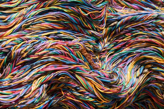 A photographic detail of an artwork by Emily Hermant made up of colourful telecommunication wires.