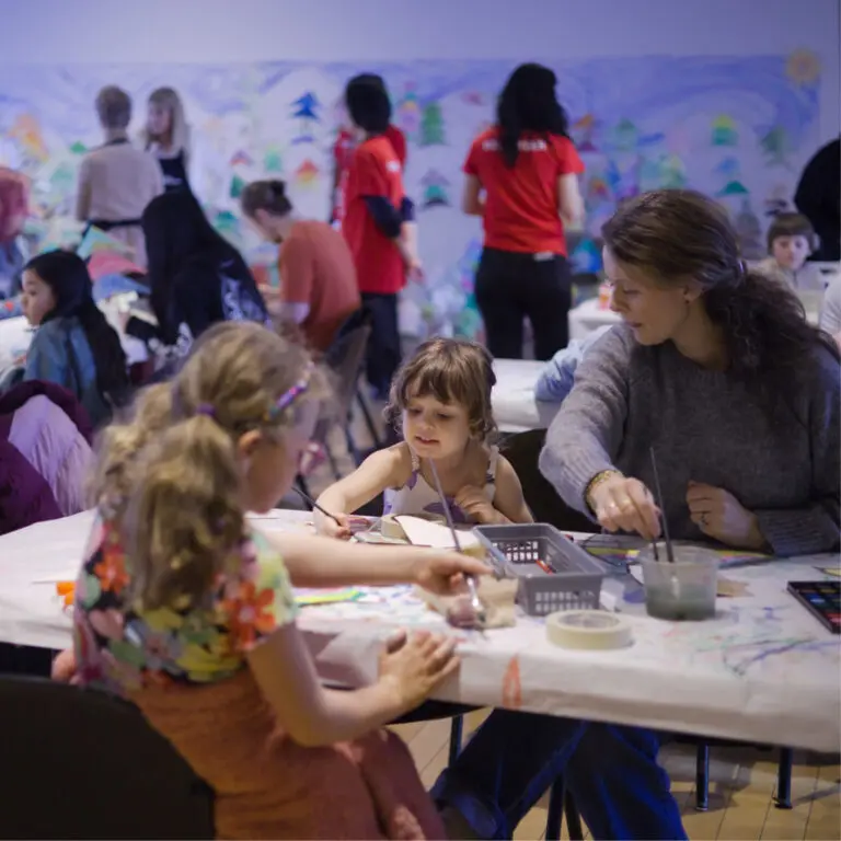 A room of families and people of all ages engaged in art-making activities at The Making Place.