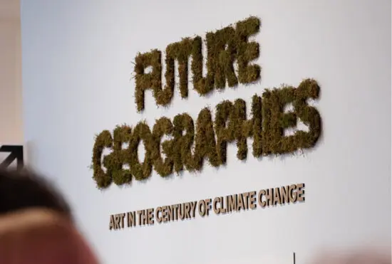 A photograph of the title wall for the exhibition Future Geographies: Art in the Century of Climate Change. The letters are made of cardboard, and there is moss adhered to them.
