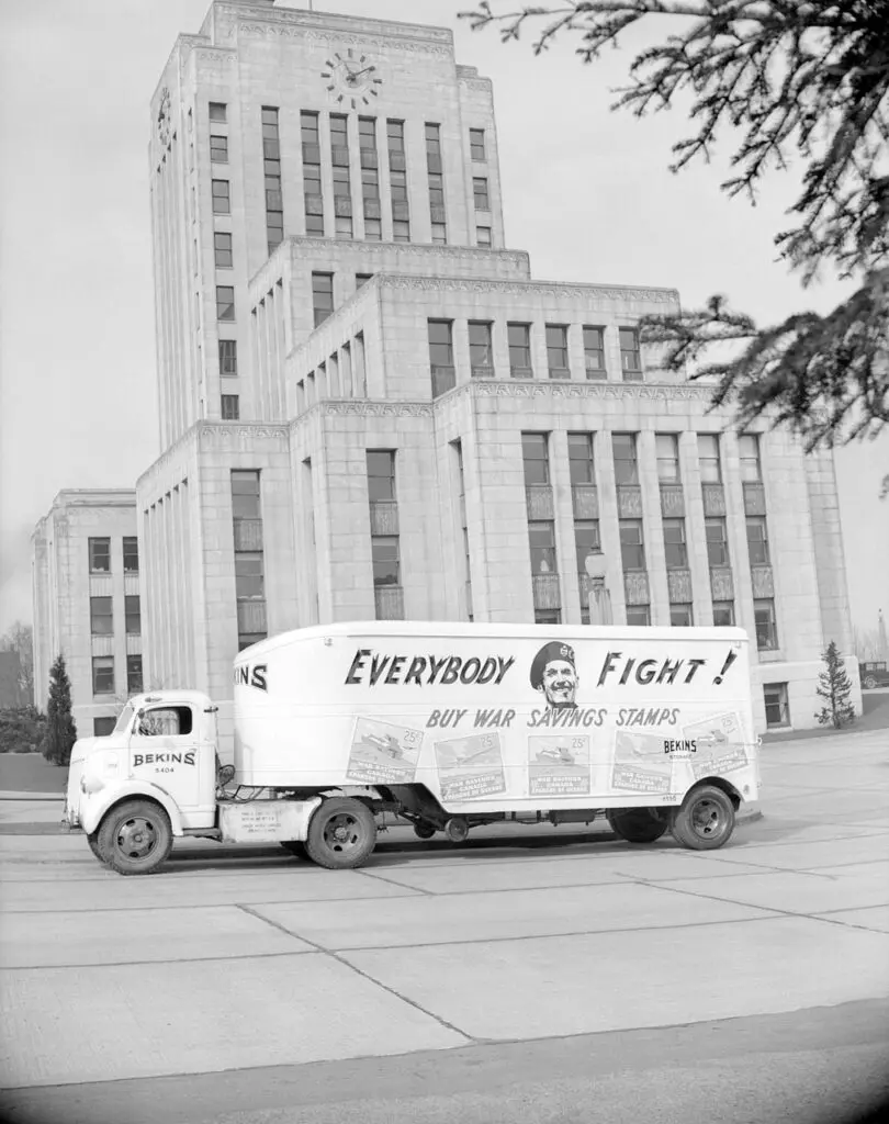 An archival photograph in black and white of Vancouver City Hall with a truck out front that reads "Everybody Fight!"