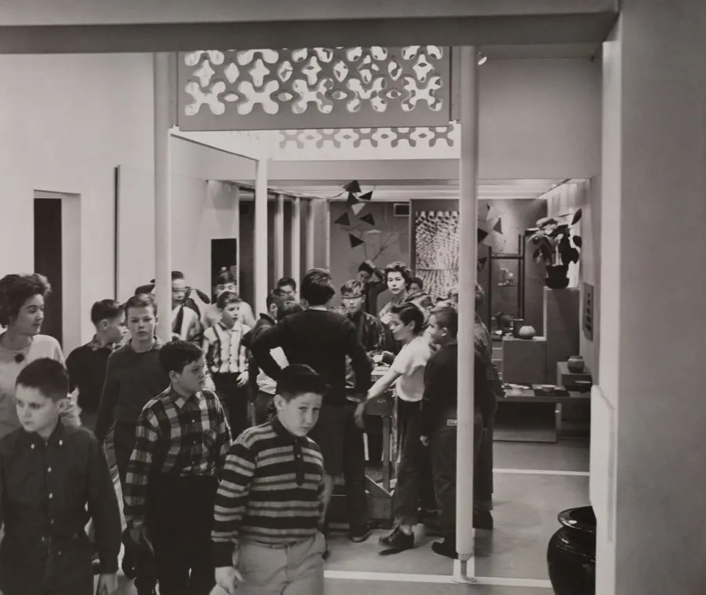 An archival photograph in black and white of children an adults visiting the Children's Gallery