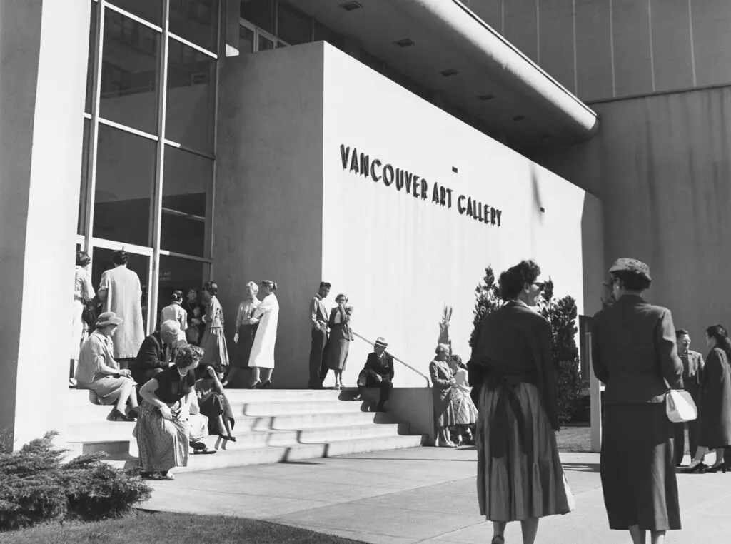 An archival photograph in black and white of the front of the Gallery, with people walking by