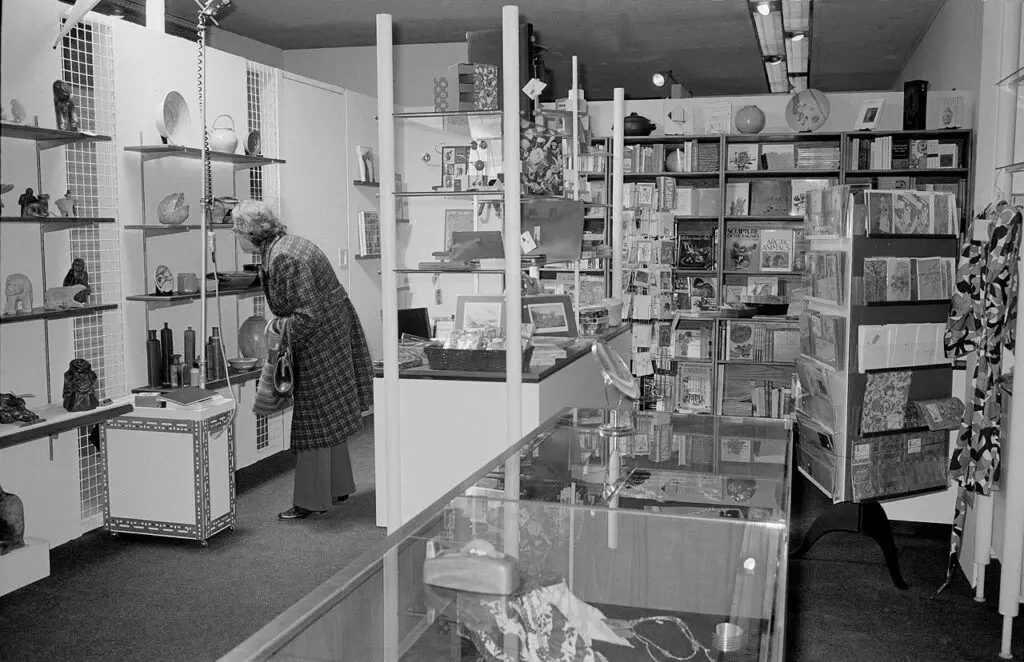 An archival photograph in black and white of a woman looking at products in the Gallery Store