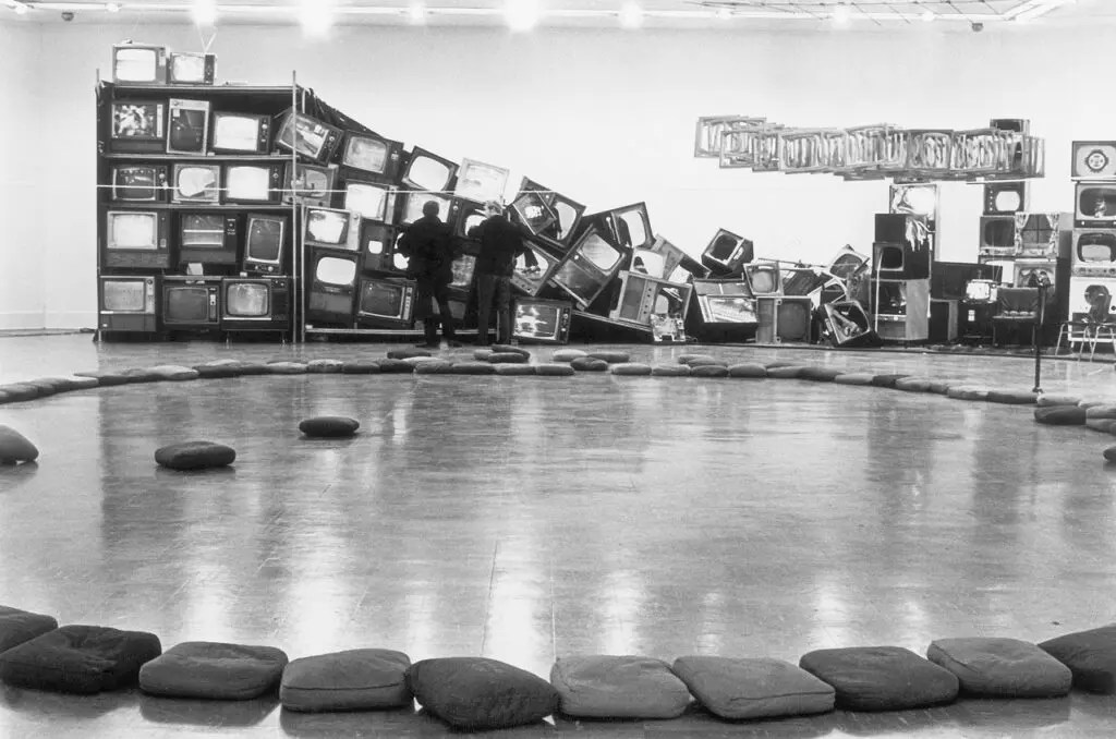An archival photograph in black and white of a performance at the Gallery. There is a circle with people performing in the background.