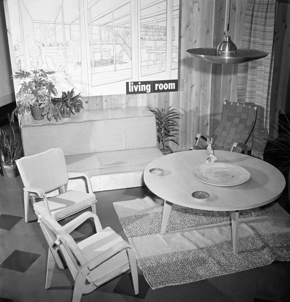 An archival image in black and white of a living room with modern furniture, including two chairs and a table
