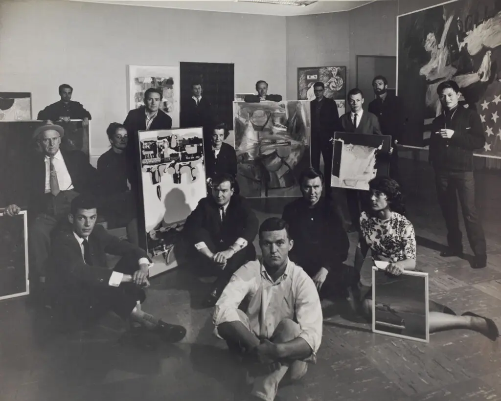 An archival photograph in black and white of a group of artists, mostly men.