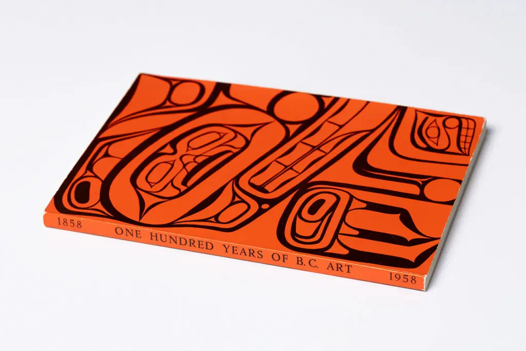 A photograph of an exhibition catalogue in red with Indigenous art on the cover.