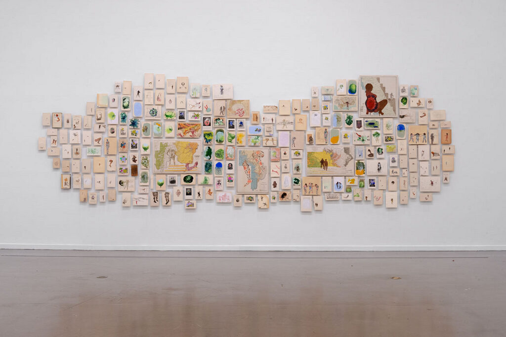 A collage of several different paintings on individual book pages hung closely together.