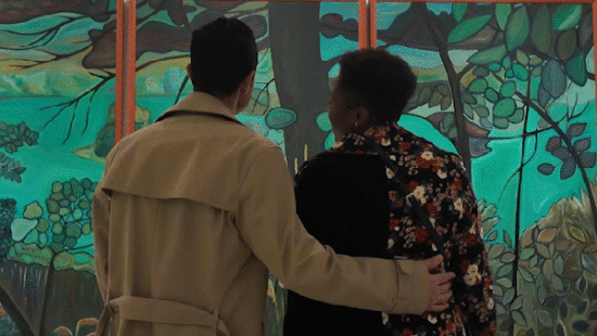 A happy couple smiles and looks at art together