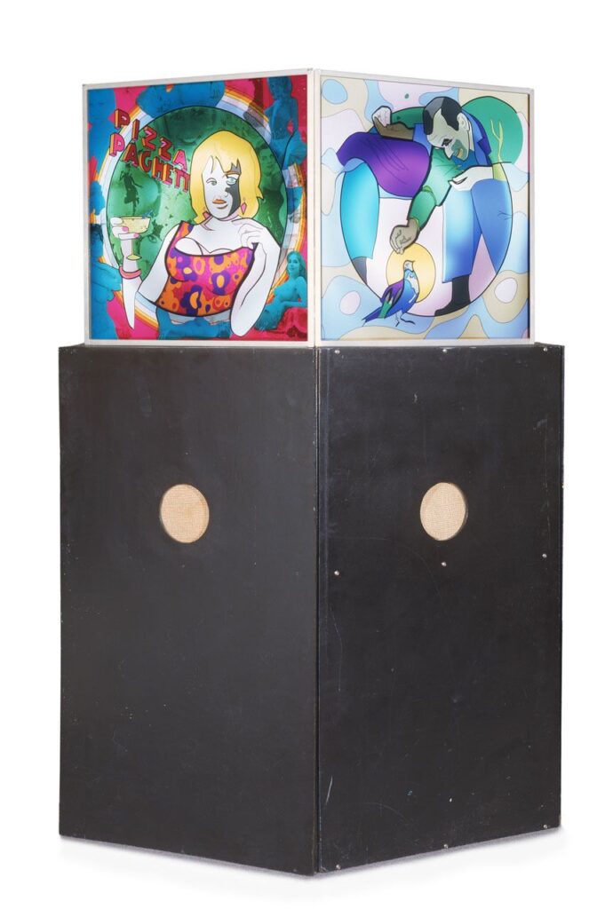 A sculptural artwork composed of a black rectangular base with two round speaker-like openings, topped by a cube featuring brightly coloured, comic-style illustrations on two visible sides. The left panel shows a blonde woman in a vibrant crop top holding a cocktail, with the text “PIZZA PAGHET” in playful letters above her. The background includes abstract rainbow rings and blue-tinted figures. The right panel depicts a man crouched down feeding a bird, rendered in smooth, curved shapes with soft gradients of blue, green and purple, set against a backdrop of rounded forms and halos.