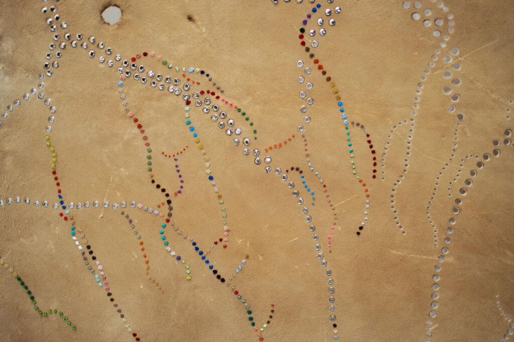 Detail look at deer with colourful thread sewn into it.