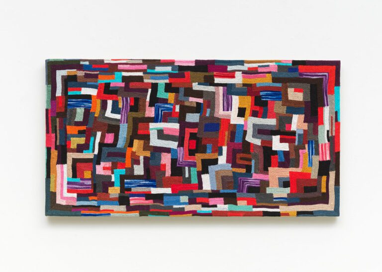 A photograph of a textile artwork by Canadian artist Jan Wade. The piece is a colourful, hand-sewn work, stretched on canvas. It looks like a mosaic.