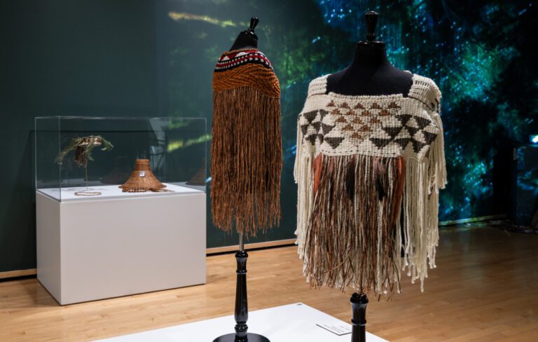 A photograph of Indigenous weavings of clothing made of cedar in the exhibition space.