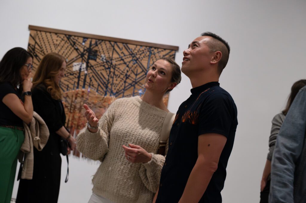 A photograph of a man and a woman standing and talking about art in the exhibition space.