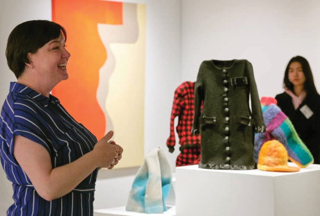 A photograph of a woman giving a tour in an art gallery setting.