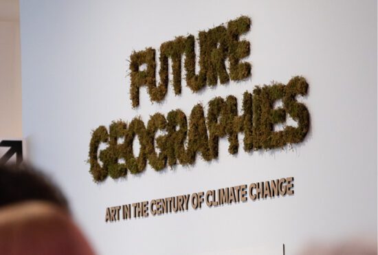 A photograph of the title wall for the exhibition Future Geographies: Art in the Century of Climate Change. The letters are made of cardboard, and there is moss adhered to them.